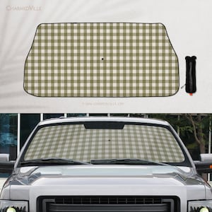 May include: A rectangular car windshield sun shade featuring a sage green and white gingham check pattern with a black border. The shade is shown both unfolded and folded into a black storage pouch, and installed inside a vehicle windshield.