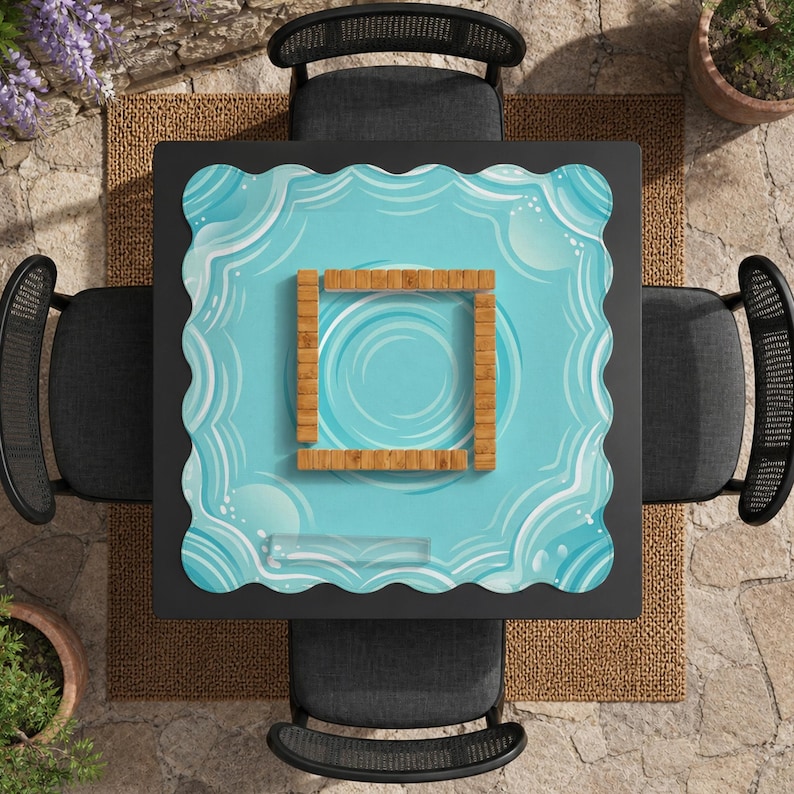 May include: Overhead view of a square black table with four black chairs. The table has a light blue placemat with a wavy border and a wooden square in the center. The placemat has a water-like design.