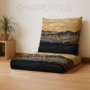 May include: A floor cushion and backrest set with a landscape design. The artwork features black, gold, and gray mountain silhouettes and gold dot accents. The text "CHARMEDVILLE" is visible at the top.