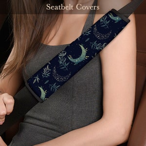 May include: A dark blue seatbelt cover with a crescent moon and star pattern. The pattern is repeated throughout the cover. The cover is made of a soft, comfortable material.