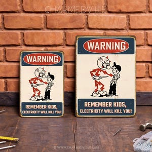 May include: Two rectangular metal signs with a vintage design. Each sign features a cartoon illustration of a figure with lightning bolts attacking a boy. The signs have the text "WARNING" and "REMEMBER KIDS, ELECTRICITY WILL KILL YOU!"