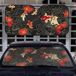 May include: Car windscreen sunshade with a koi carp and floral design. The pattern features red, white, and gold koi carp swimming among red flowers and gold swirls on a black background. The sunshade is designed to fit a car windscreen.
