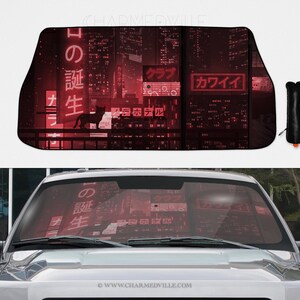 Op de afbeelding: Auto zonnescherm met een rood stadsgezicht, Japanse tekst en een zwart katten silhouet. Het zonnescherm is zwart en wordt geleverd met een zwarte opbergtas.