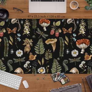 Puede incluir: Un ratón de ordenador ilustrado en blanco y negro con un patrón repetitivo de setas, mariposas, caracoles y helechos. El ratón mide 47 x 23,5 pulgadas o 120 x 60 centímetros.