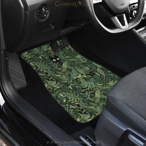 May include: Green car floor mats with a black cat pattern. The cat is peeking out from behind green leaves. The mats have the text "www.charmedville.com" on the bottom.