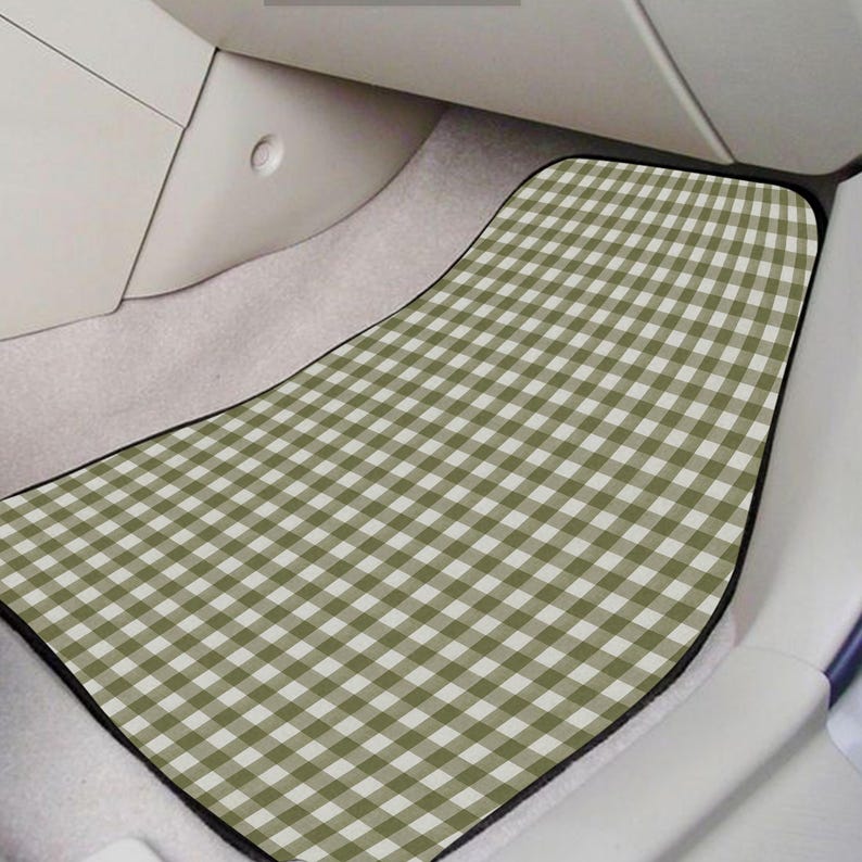May include: A car floor mat featuring a sage green and white gingham check pattern. The mat has a contoured shape with rounded corners and a black border, designed to fit the footwell area of a vehicle interior with light-colored carpeting.