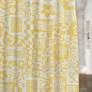 May include: Yellow and white shower curtain with a patchwork design. The design includes flowers, smiley faces, and text such as "Positive Vibes Only" and "Focus on the Good". The curtain is in a bathroom setting.