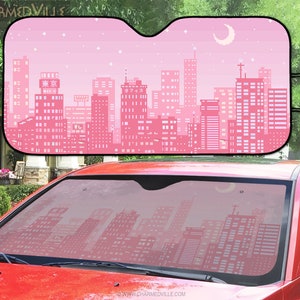 May include: Pink and white car sunshade with a pixelated city skyline design. The skyline features buildings with Japanese text, a crescent moon, and stars.