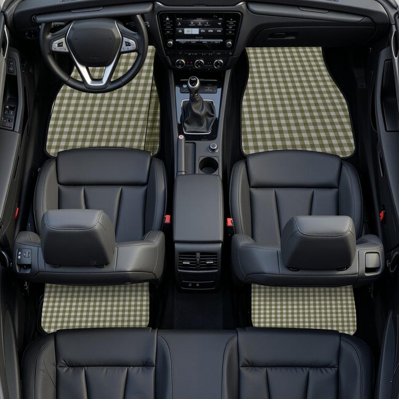 May include: A car interior featuring black leather seats and a steering wheel, equipped with custom floor mats that display a repeating olive green and white gingham check pattern across the front and rear footwell areas of the vehicle.