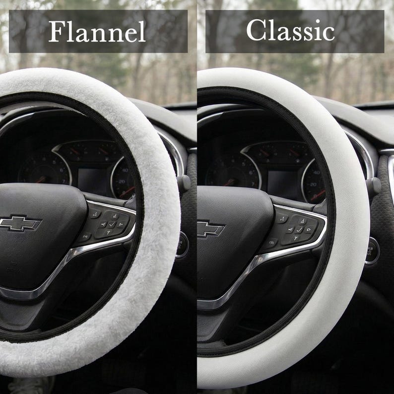 Peut inclure: Deux housses de volant, l'une avec une texture Flannel blanche et duveteuse, l'autre avec une texture Classic blanche et lisse. Les housses sont pr&eacute;sent&eacute;es sur un volant noir avec des accents argent&eacute;s. Le tableau de bord est visible.
