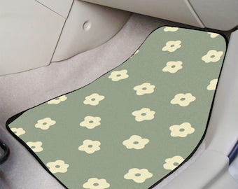 May include: A green car floor mat with a white floral pattern. The mat has a black border.