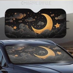 May include: A black car sunshade with a gold crescent moon and stars on a dark blue background. The sunshade features a stylised design of clouds and stars.