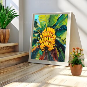 May include: A framed art print depicting a vivid painting of a cluster of yellow bananas set against large green leaves. The artwork is presented in a white frame, creating a strong contrast. The painting captures the essence of a tropical scene.