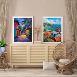 Pu&ograve; includere: Due stampe artistiche incorniciate raffiguranti scene tropicali. Una mostra una strada colorata con edifici e palme, l'altra una vista costiera con mare blu e case con tetti rossi. Le stampe sono esposte su un mobile in legno chiaro.