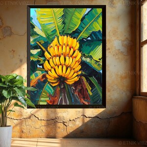 May include: A colourful painting of a cluster of yellow bananas, contrasted by large green banana leaves. The artwork is framed in black and hangs on a textured, light-coloured wall, with a potted plant in the foreground.