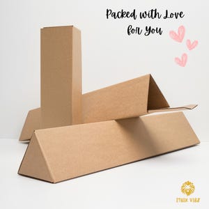 May include: Several brown cardboard shipping boxes are arranged on a white surface. The boxes are in various shapes, including rectangular and triangular prisms. The text "Packed with Love for You" is written in black script, with pink heart illustrations.