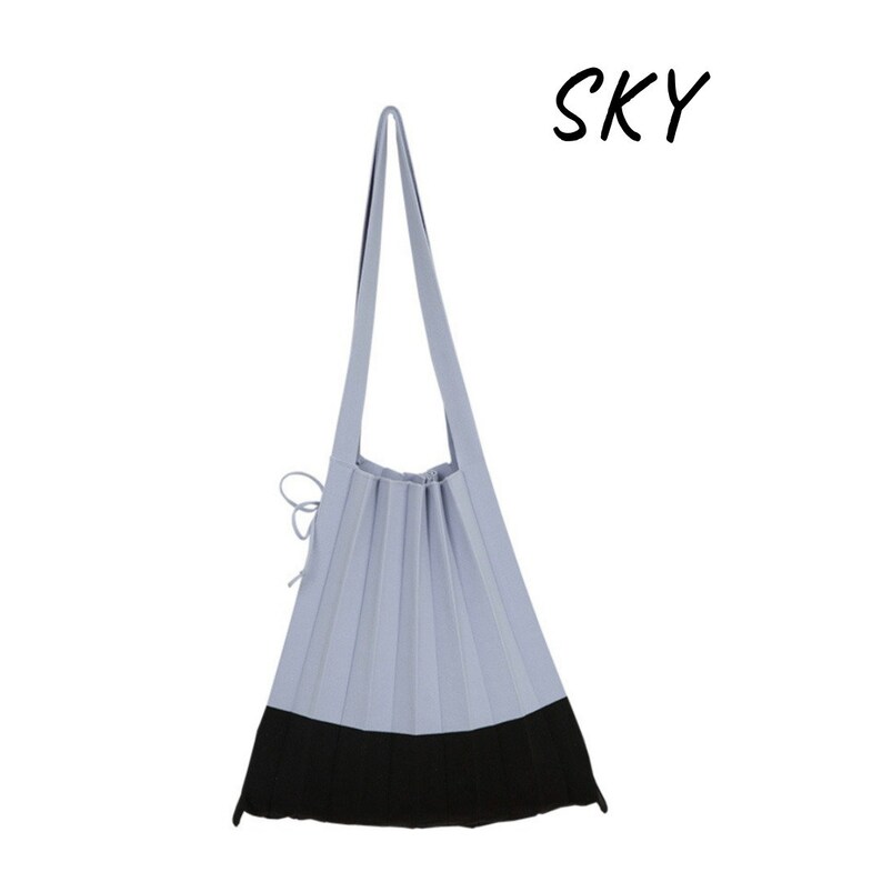 May include: A light blue pleated tote bag with a black bottom. The bag has a single strap and a drawstring closure. The word "SKY" is written in black above the bag.