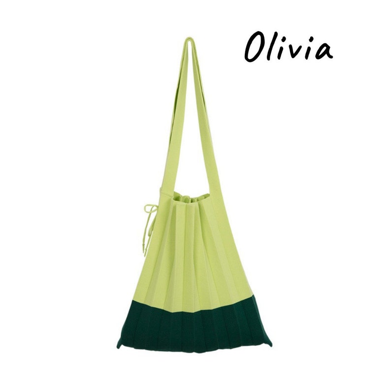May include: A light green and dark green pleated tote bag with a single strap. The bag has the word "Olivia" written in black cursive on a white background.