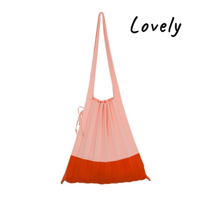 May include: A pink and orange pleated tote bag with long straps. The bag has a drawstring closure.