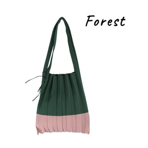 May include: A green and pink pleated tote bag with a long strap. The bag has a forest green top and a pink bottom.
