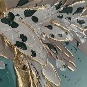 Op de afbeelding: Abstract schilderij met textuurstreken in tinten wit, grijs, goud en teal. Het schilderij heeft een grote, abstracte vorm die lijkt op een vleugel of een blad.
