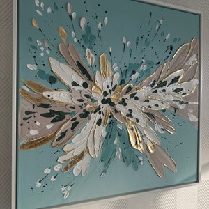 Op de afbeelding: Abstract schilderij met een teal achtergrond en een groot, getextureerd, wit, goud en bruin bloemendesign.