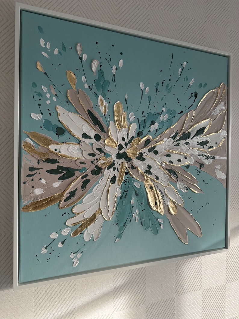 Op de afbeelding: Abstract schilderij met een teal achtergrond en een groot, getextureerd, wit, goud en bruin bloemendesign.