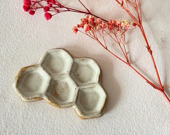 Könnte beinhalten: Eine weiße Keramik-Farbpalette in Form einer Wabe mit sechs einzelnen Vertiefungen. Die Palette hat eine hellbraune Glasur.