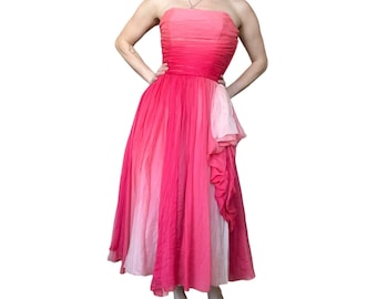 May include: A strapless ombre pink and white dress with a gathered bodice and a flowing skirt. The dress has a ruffled detail on the side.