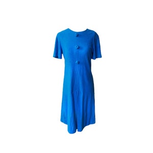 Puede incluir: Un vestido azul brillante de manga corta con cuello redondo y tres botones decorativos en la parte delantera.
