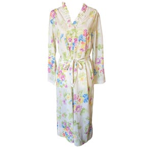 May include: A long, cream-colored robe with a floral pattern in shades of pink, blue, yellow, and green. The robe has long sleeves, a V-neck with a ruffled trim, and a matching tie belt. The fabric appears lightweight.
