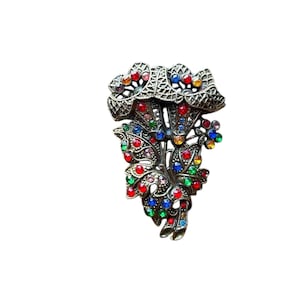Könnte beinhalten: Eine Vintage-Brosche mit einem floralen Design mit mehrfarbigen Strasssteinen. Die Brosche ist aus Metall und hat ein detailliertes Filigran-Design.