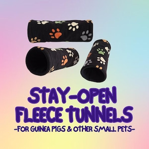Peut inclure: Trois tunnels en polaire noire pour petits animaux, ornés d'un motif d'empreintes de pattes orange, vertes et blanches. Le texte ci-dessous indique STAY-OPEN FLEECE TUNNELS -FOR GUINEA PIGS & OTHER SMALL PETS- en lettres violettes.
