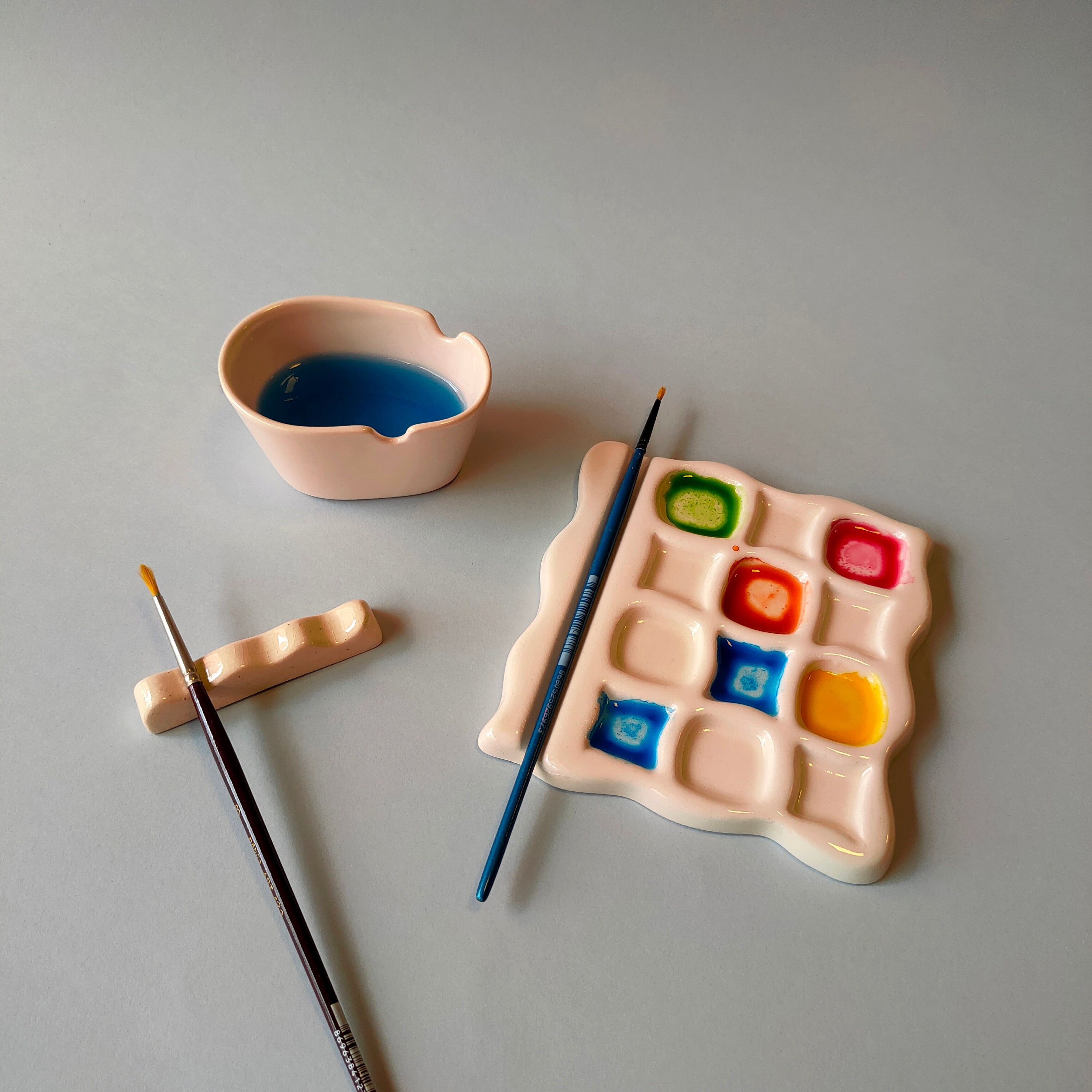 Set of painting tools: ceramic paint palette, water paint cup, brush rest.  Artist's tools, ceramic b rush holder