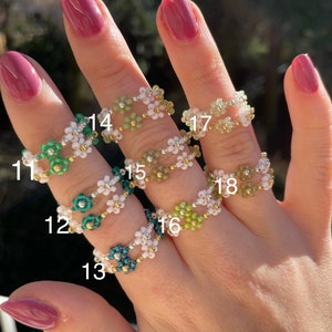 Puede incluir: Un conjunto de diez anillos de cuentas con dise&ntilde;os de flores en varios colores, incluyendo verde, blanco y azul. Los anillos est&aacute;n numerados del 11 al 18.