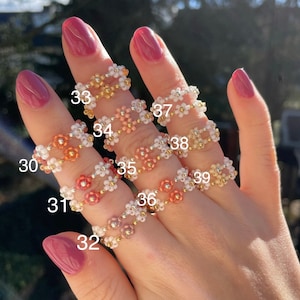 Puede incluir: Nueve anillos de cuentas con dise&ntilde;os de flores en varios colores, incluyendo blanco, rosa, naranja y dorado. Los anillos est&aacute;n numerados del 30 al 39.