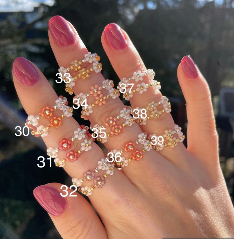 Puede incluir: Nueve anillos de cuentas con dise&ntilde;os de flores en varios colores, incluyendo blanco, rosa, naranja y dorado. Los anillos est&aacute;n numerados del 30 al 39.