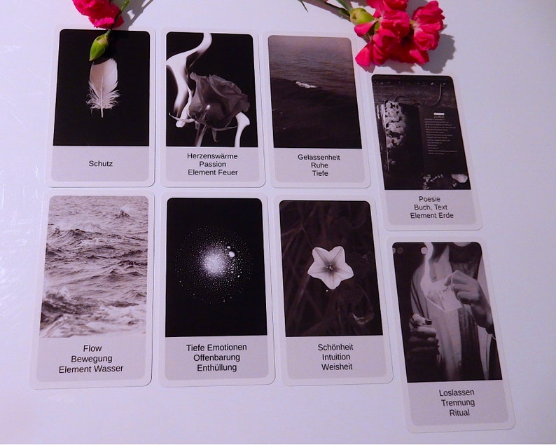 May include: A set of ten black and white tarot cards with German text. The cards depict images of a feather, fire, water, a flower, a book, a star, a flower, a hand holding a lighter, and a wave.