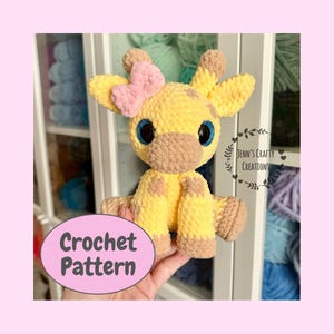 May include: Crocheted giraffe amigurumi toy with a pink bow, brown spots, and blue eyes. The toy is being held by a hand. The image includes the text "Crochet Pattern".
