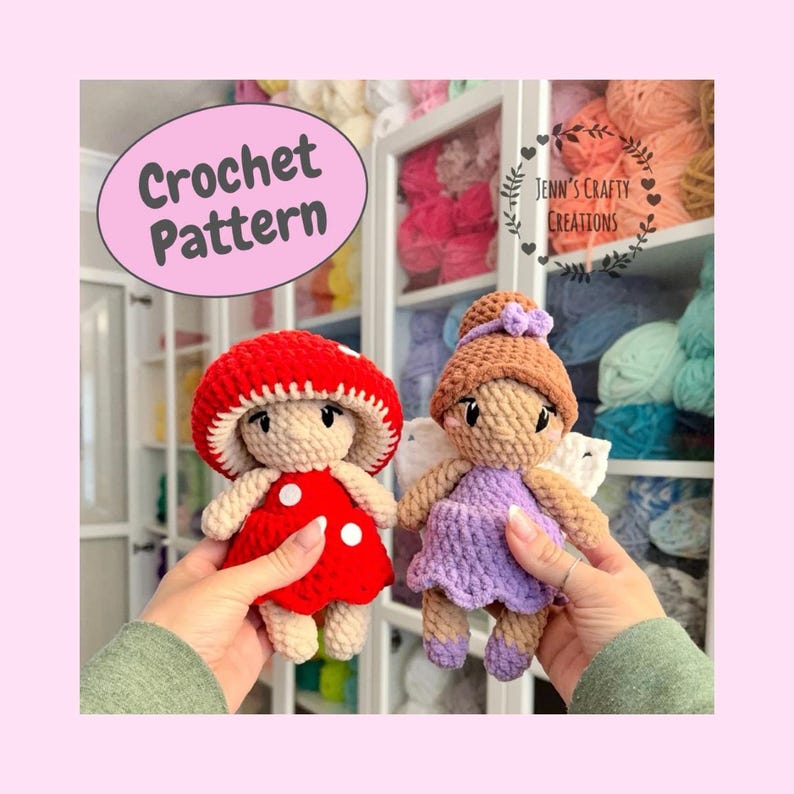 K&ouml;nnte beinhalten: Zwei geh&auml;kelte Amigurumi-Puppen, eine mit einem roten Pilz-Hut und die andere mit lila Fl&uuml;geln und einem braunen Dutt. Die Puppen halten ein rotes und wei&szlig;es Herz mit dem Text "Jenn's Crafty Creations".