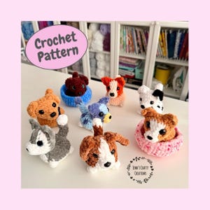 May include: A selection of crocheted dog toys in shades of brown, grey, and white. Some dogs are nestled in small crochet baskets. The image features the text "Crochet Pattern" and "Jenn's Crafty Creations".
