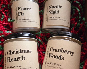 Könnte beinhalten: Vier Gläser mit Sojawachskerzen mit schwarzen Deckeln und beigen Etiketten. Die Etiketten lauten "Fraser Fir", "Nordic Night", "Christmas Hearth" und "Cranberry Woods". Jede Kerze wiegt 170g und ist handgegossen in Pennsylvania.