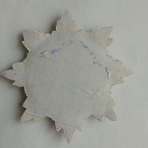 May include: A white paper star with a jagged edge. The star has blue and pink markings on the back.