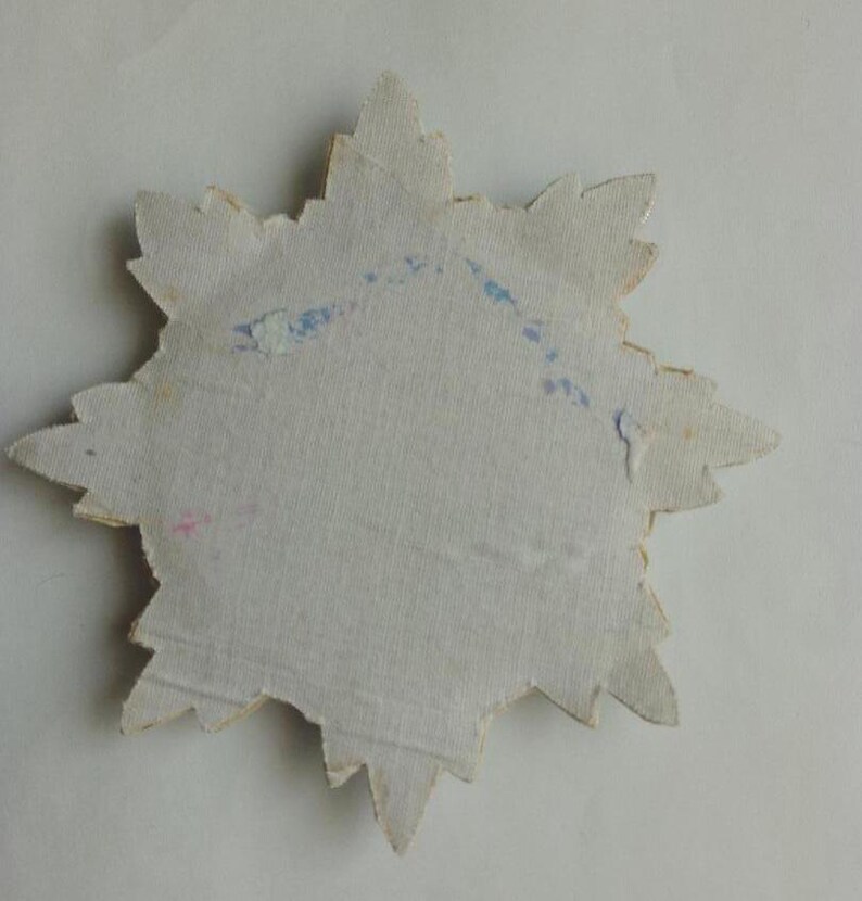 May include: A white paper star with a jagged edge. The star has blue and pink markings on the back.