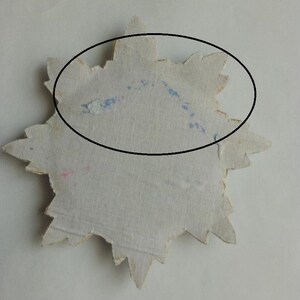 May include: A white star-shaped paper cutout with blue and pink markings. The star is slightly faded and has a rough texture.