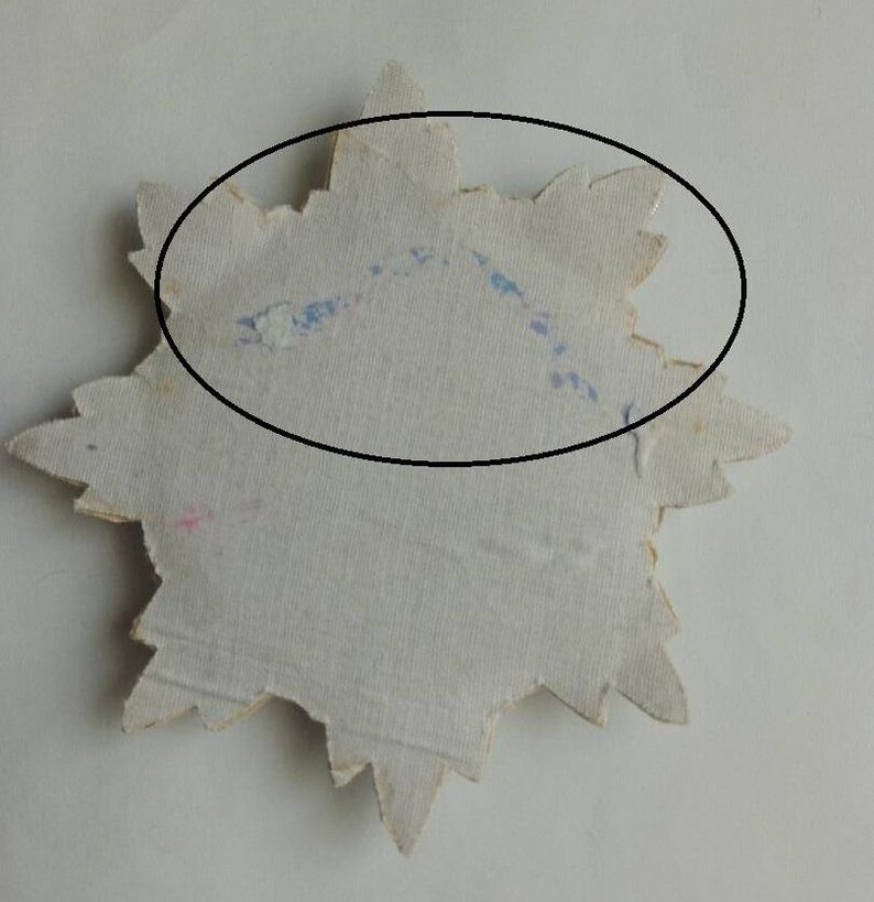 May include: A white star-shaped paper cutout with blue and pink markings. The star is slightly faded and has a rough texture.