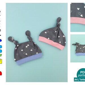 Op de afbeelding: Twee grijze gebreide baby mutsen met witte hartjespatronen en contrasterende gekleurde rand. De mutsen hebben geknoopte bandjes aan de bovenkant. De mutsen liggen op een lichtblauwe achtergrond. De tekst "JULAWW! patterns" staat in de linkerbovenhoek van de afbeelding. De tekst "PDF pattern A4 / letter / A0" staat in de rechterbenedenhoek van de afbeelding.