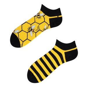 Könnte beinhalten: Zwei Paar Knöchelsocken. Ein Paar hat ein gelbes und schwarzes Streifenmuster. Das andere Paar hat ein gelbes Wabenmuster mit schwarzen Bienen.