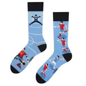 Könnte beinhalten: Ein Paar Sportsocken mit hellblauem Hintergrund und schwarzem Oberteil und Zehen. Die Socken zeigen Illustrationen von Handballspielern in Aktion. Das Wort "TODO" ist auf die Seite jeder Socke gedruckt.