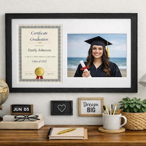 May include: A black framed graduation photo and certificate. The photo shows a graduate in a cap and gown holding a diploma. The certificate reads "Certificate of Graduation" with a name and the year "Class of 2022".